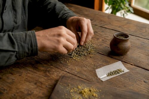 Hände mischen CBD-Pollen in einer Kräutermischung für Joints
